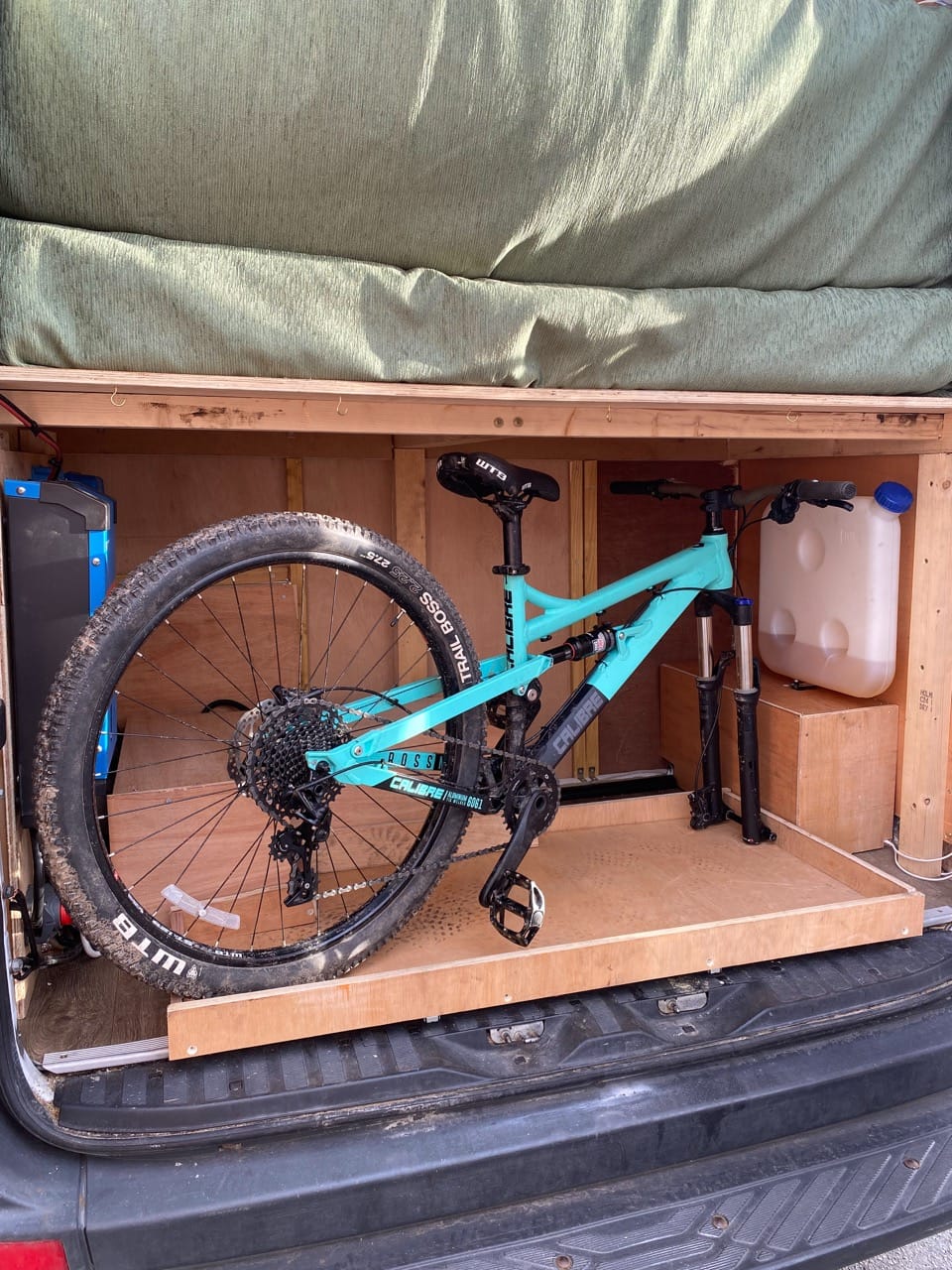 Blue mountain bike in an under floor compartment in a van