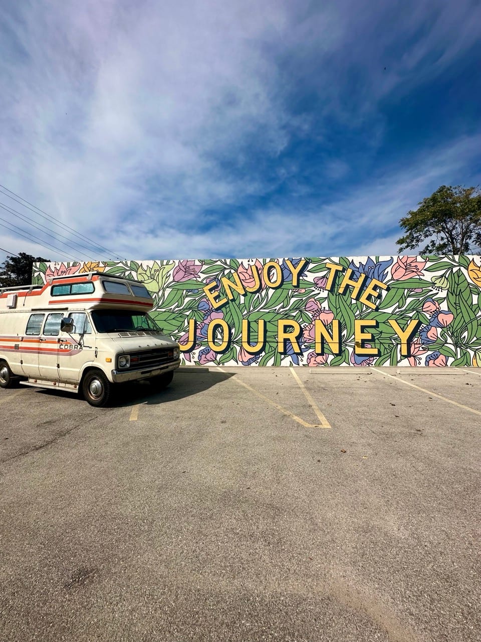 Vintage van next to a mural with the words enjoy the journey