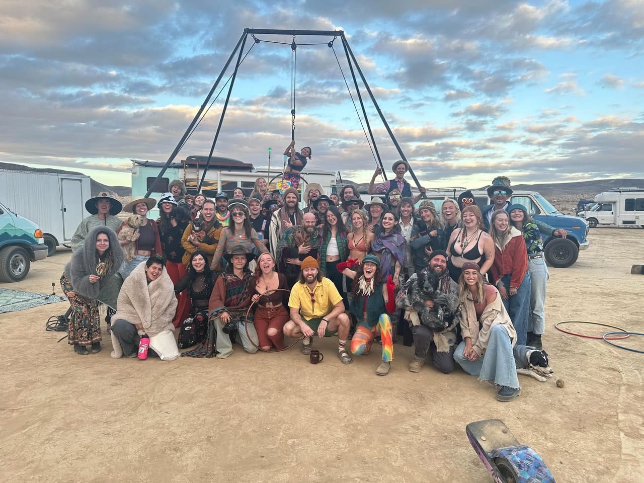 A large group of vanlifers posing for a group pic surrounded by their vehicles