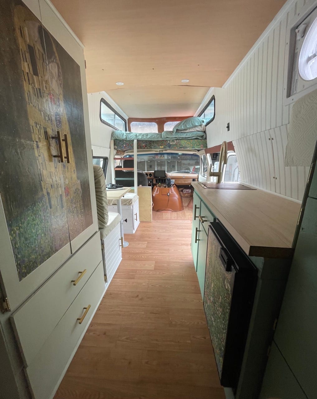 Interior of a campervan with kitchenette, breakfast nook, and bed