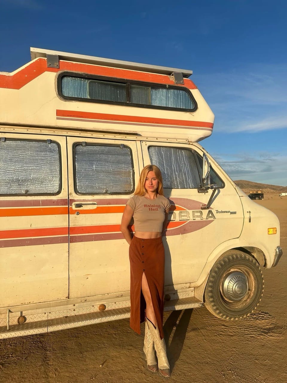 Young woman standing in front of a retro campervan